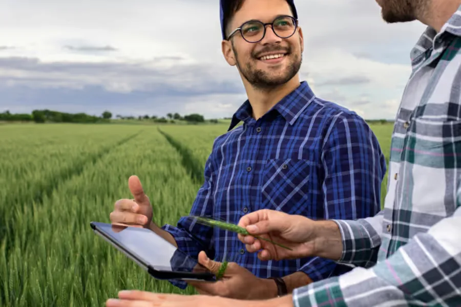 Productores en el campo consultando el control remoto de riego Reinke en un dispositivo móvil